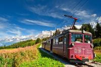 a red train on the tracks in the mountains at Résidence Grand Roc - Bruyères 022 - Happy Rentals in Chamonix