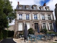 a building with tables and chairs in front of it at La maison de famille Limoges in Limoges