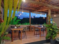a restaurant with tables and chairs on a wooden deck at Pousada Mon Gâté in Japaratinga