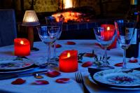 a table with candles and wine glasses on a table with a fireplace at Les Folies d'Hélène in Mailly
