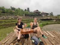 萨帕Khen Mong Nature Hotel的两个坐在桌子边喝着饮料的女人