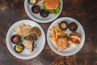 drei Teller Essen auf einem Holztisch in der Unterkunft Hotel Michanti in El Zonte