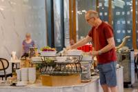 een man die eten klaarmaakt op een tafel met een dienblad met borden bij Sukhothai Treasure Resort & Spa in Sukhothai