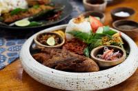 a bowl of food on a table with plates of food at Unagi Wooden Villas by Emana in Ubud
