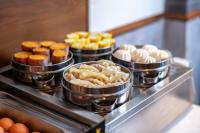 a bunch of muffins and donuts in tin pans on a stove at Nostalgia S Hotel Kunming Old Street in Kunming