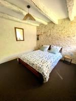 a bedroom with a bed in a stone wall at Gîte de la Grange in Colombiers