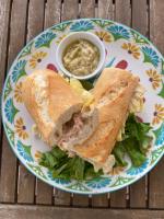 un panino tagliato a metà su un piatto con salse di Hotel Rondinella e Viola a Rimini