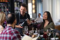 a man holding a bottle of wine in a restaurant at The Gainsborough Bath Spa - Small Luxury Hotels of the World in Bath