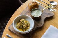 Un tazón de comida en una bandeja de madera con un tazón de mantequilla. en The Haughmond, en Shrewsbury