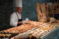 a chef standing in front of a buffet of food at Marriott Executive Apartments Downtown, Abu Dhabi in Abu Dhabi
