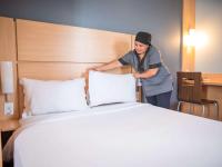 a woman standing next to a bed in a hotel room at ibis Itu Plaza Shopping in Itu