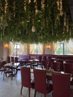 La Nature Hotels & Resorts في Sīkar: مطعم به طاولات وكراسي وزهور معلقة من السقف