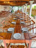 una larga hilera de mesas y sillas de madera en The barns villas and restaurant, en Negombo