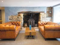 ein Wohnzimmer mit 2 Ledersofas und einem Kamin in der Unterkunft Beautiful Cornish Getaway - Newperran Holiday Resort in Cubert