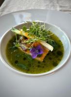 uma tigela branca de sopa com uma flor roxa dentro. em Le Mange Grenouille em Bic