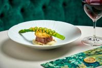 a plate of food with peas and meat and a glass of wine at Matfen Hall Hotel, Golf & Spa in Matfen