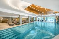 a large swimming pool in a hotel lobby with chairs at Kenese Bay Garden Resort & Conference in Balatonkenese