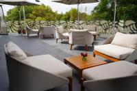 Un patio con sillas y mesas blancas y sombrillas. en Cartesiano Boutique & Wellness Hotel, en Puebla