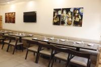 een eetkamer met tafels en stoelen en schilderijen aan de muur bij Hotel Stay Casa in Bhopal