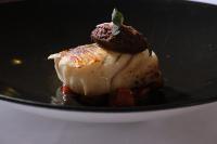 un trozo de comida en un plato negro en Hotel Spa Villa Nazules, en Chueca