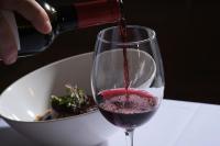 una persona que vierte vino tinto en una copa de vino en Hotel Spa Villa Nazules, en Chueca