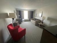 ein Hotelzimmer mit einem roten Stuhl und einem Sofa in der Unterkunft Country Inn &amp; Suites by Radisson, Council Bluffs, IA in Council Bluffs