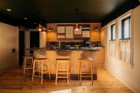 a kitchen with a bar with four stools at Somewhere Inn Collingwood in Collingwood