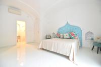 a white bedroom with a bed with a blue headboard at Casa Mulini in Positano