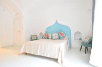 a white bedroom with a bed with a blue headboard at Casa Mulini in Positano