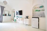 a kitchen with white cabinets and a tv on the wall at Casa Mulini in Positano