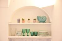 a shelf filled with green glass vases and plates at Casa Mulini in Positano