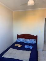 a bed with a blue comforter and two clothes on it at Casarão Hostel in Guaratinguetá