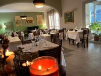 un comedor con mesas y sillas blancas y una habitación con ventanas en Locanda La Guienda, en Torre Canavese
