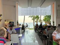 Olimpos Beach Hotel by RRH&R في كيمير: مجموعة من الناس يجلسون في مطعم مع الشاطئ