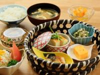 上山市にあるステイインホテル材木栄屋のさまざまな種類の食べ物が入ったボウルが置かれた木製のテーブル