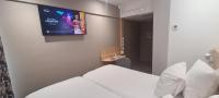 a hotel room with a tv on the wall at Geographotel Paris-Roissy CDG Airport in Le Mesnil-Amelot