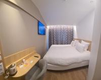 a small bedroom with a bed and a table at Geographotel Paris-Roissy CDG Airport in Le Mesnil-Amelot