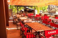 Un restaurante al aire libre con sillas rojas y mesas de madera. en Hotel Valle Grande, en San Rafael
