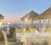 a restaurant with white tables and chairs and the ocean at spazioso bicamere fronte mare in Marina di Strongoli