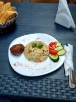 un plato de comida con arroz y verduras en una mesa en MAHALI HOTEL, en Batumi