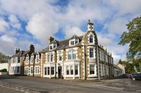 a large brick building with white windows on a street at Ulbster Arms Hotel near Thurso in Halkirk
