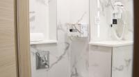 a bathroom with white marble walls and a phone at Geographotel Paris-Roissy CDG Airport in Le Mesnil-Amelot