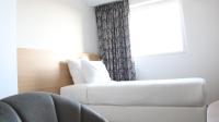 a white couch in a room with a window at Geographotel Paris-Roissy CDG Airport in Le Mesnil-Amelot