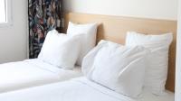 a white bed with white pillows on it at Geographotel Paris-Roissy CDG Airport in Le Mesnil-Amelot
