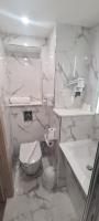 a white bathroom with a toilet and a sink at Geographotel Paris-Roissy CDG Airport in Le Mesnil-Amelot