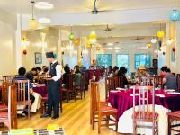 um empregado de mesa num restaurante com pessoas sentadas às mesas em Royal Resort, itahari em Itahari