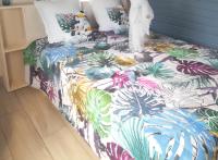 a bed with a colorful comforter with plants on it at Bungalow d&#39;une chambre avec jardin clos et wifi a Le moule in Le Moule