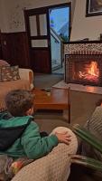 a young boy sitting on a couch in front of a fireplace at Pousada Sino dos Ventos in Campos do Jordão