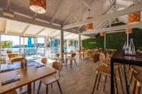 a restaurant with wooden tables and chairs and windows at Palm Beach Cottage with Private Spa Pool in Palm Beach