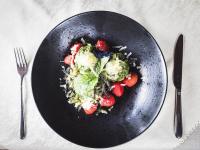 a black plate of food with strawberries and broccoli at Prissianerhof in Tesimo